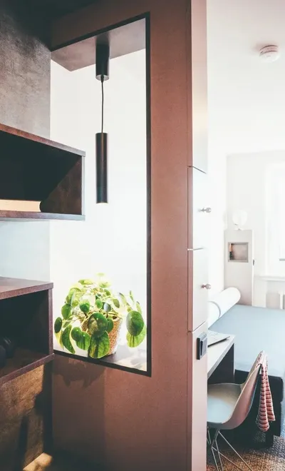 Modernes Hotelzimmer mit offenem Kleiderschrank, Schreibtisch und Bett im Hintergrund.