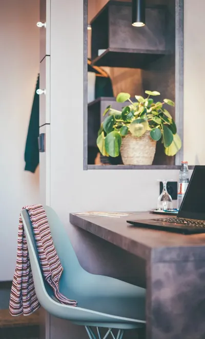 Schreibtisch mit Laptop, Stuhl und Pflanze in modern eingerichtetem Zimmer