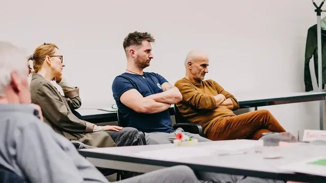 Mehrere Personen sitzen in einem Seminarraum an einem Tisch, auf dem Moderationsmaterialien liegen.