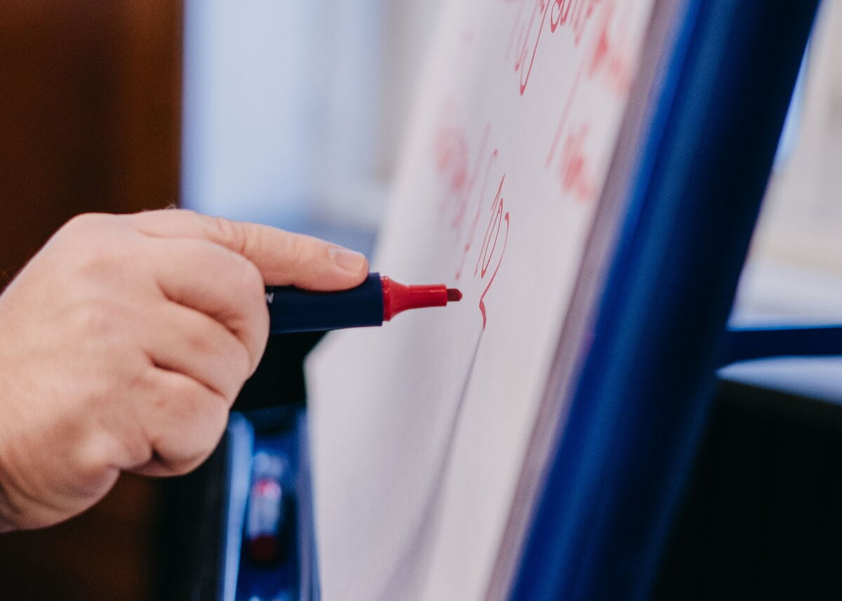 Roter Stift schreibt auf Plakat.