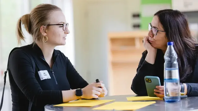 Zwei Frauen stehen am Stehtisch und unterhalten sich