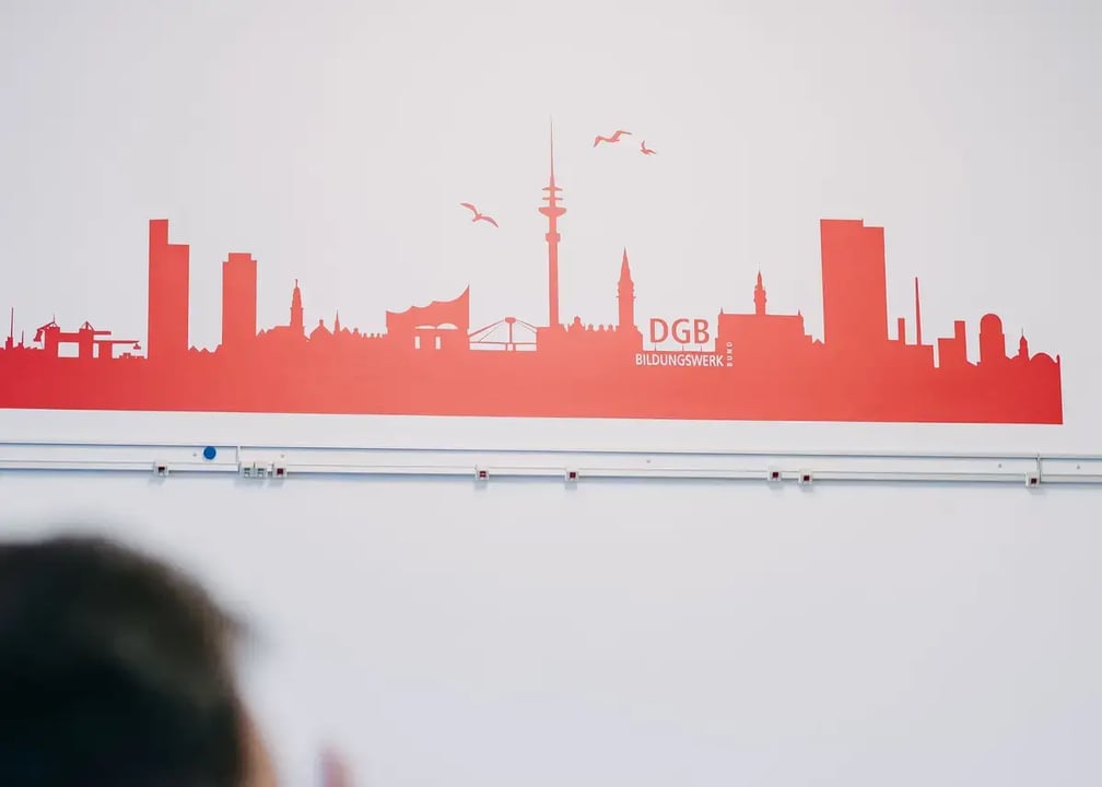 Rote Wandgrafik mit der Skyline einer Stadt und dem Schriftzug „DGB Bildungswerk“.