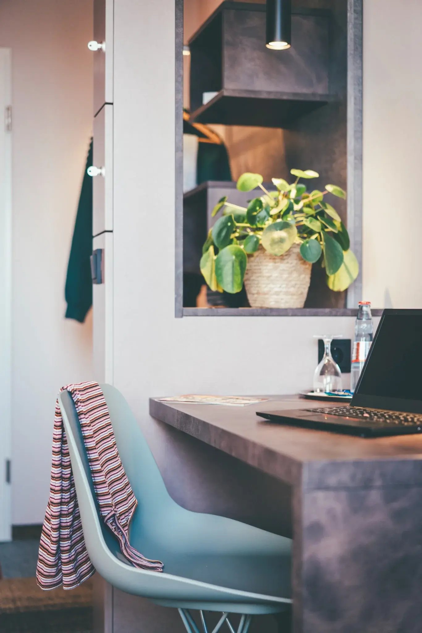 Schreibtisch mit Laptop, Stuhl und Pflanze in modern eingerichtetem Zimmer