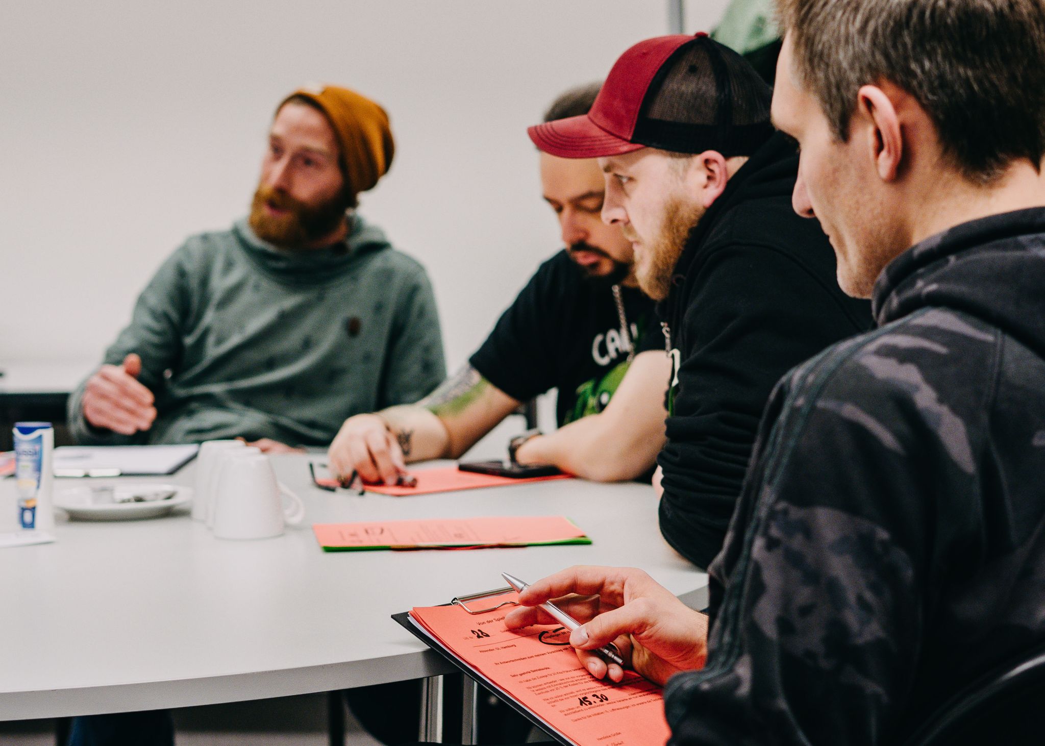 Teilnehmende sitzen an einem Tisch und bearbeiten Unterlagen in einem Seminar.