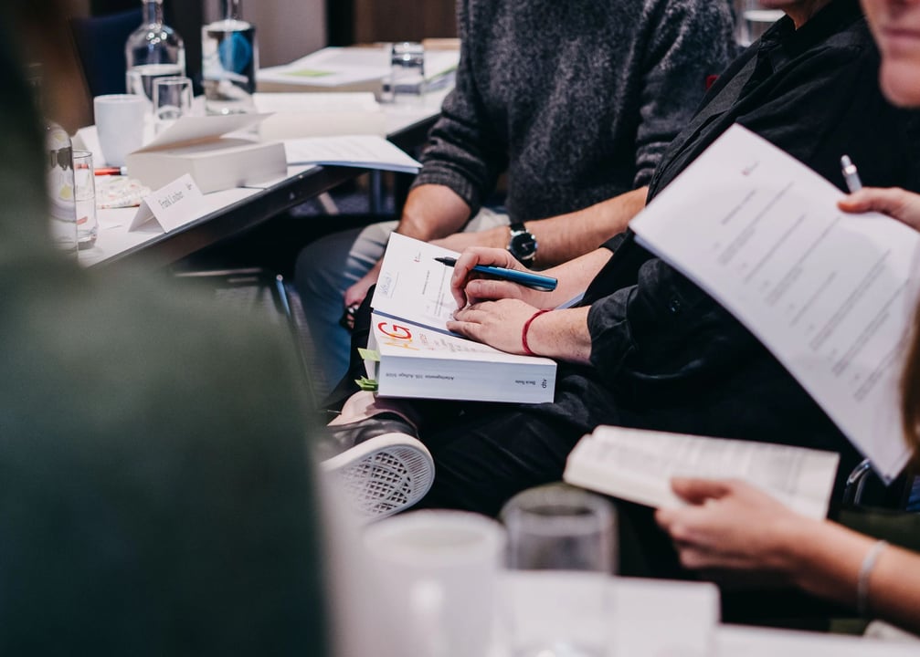 Person sitzt am Tisch und macht sich Notizen