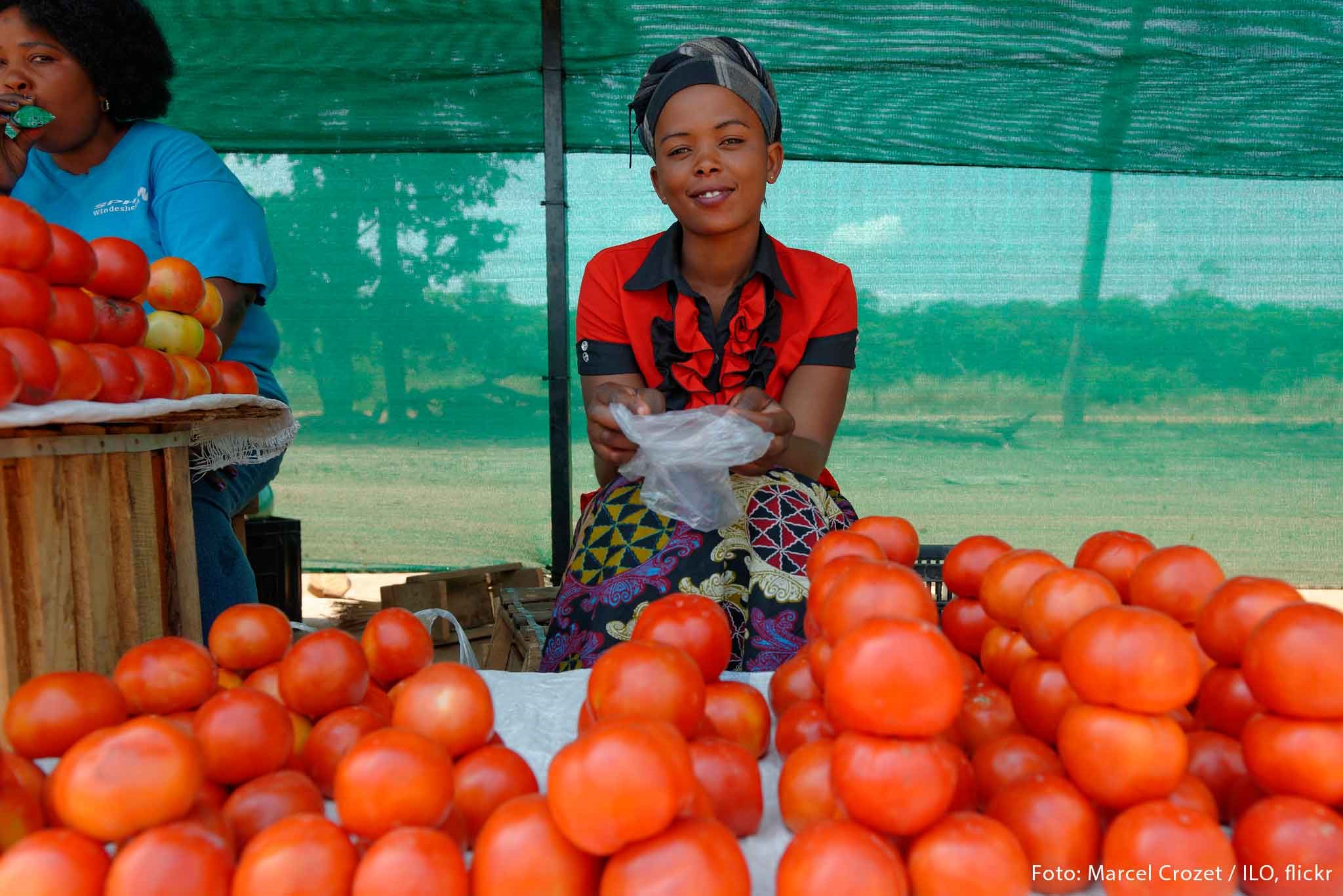 Frau verkauft Tomaten an einem Stand.