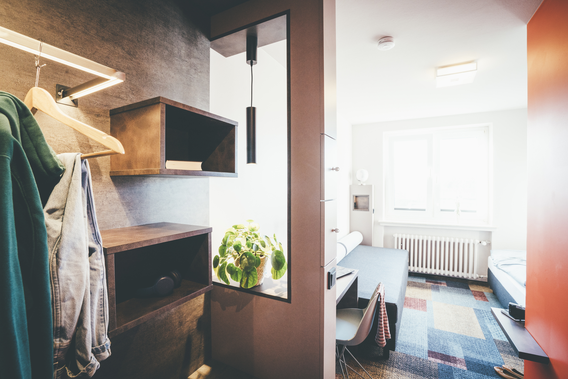 Ein Zimmer im DGB Tagungszentrum Hattingen mit einem Kleiderschrank, einem Kleiderständer und einem Regal.