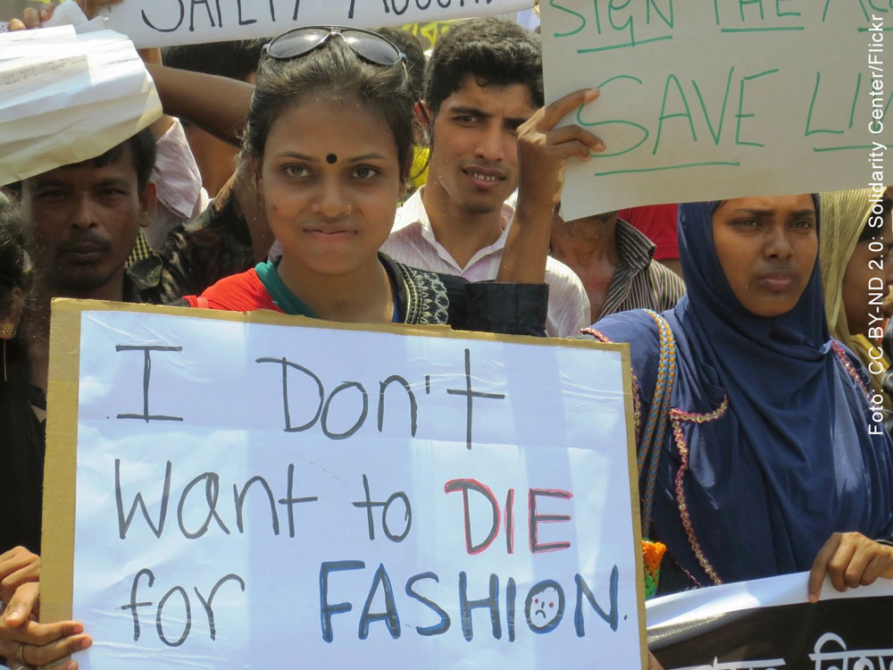 Arbeiter*innen mit Protestschildern in Bangladesch. Auf einem steht: I don't want to die for fashion.