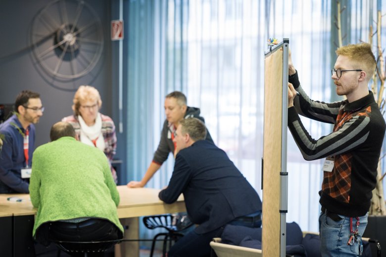5 Personen diskutieren in einer Arbeitsphase und eine Person notiert Ergebnisse.
