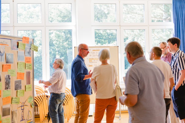 Eine Gruppe von Teilnehmenden steht im Raum und diskutiert. 